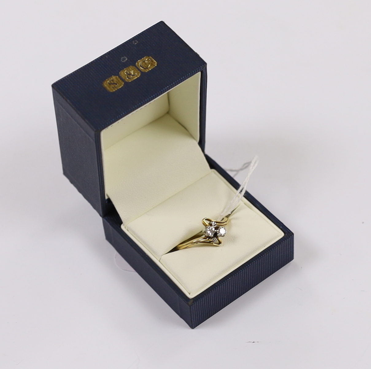A yellow metal and graduated four stone diamond set crossover ring, size R, gross weight 3.4 grams.